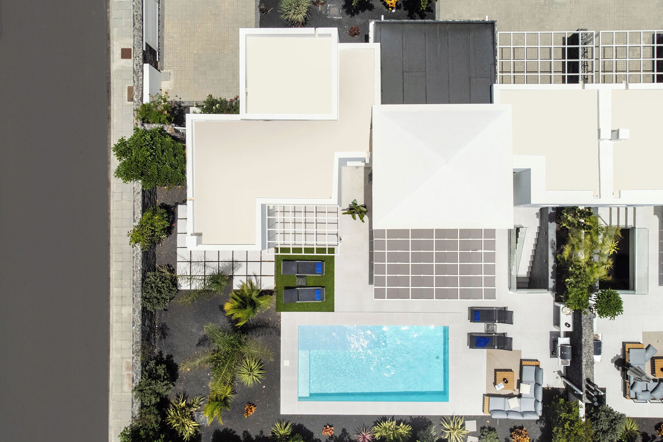 A modern hotel with a rooftop pool, outdoor seating, and a landscaped garden.