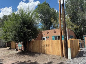 A wooden structure with a sloped roof, surrounded by trees and a wooden fence. - STR #03015 - Steps to Main St, Near Sand Dunes (Alamosa)