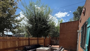 Un patio al aire libre con cerramiento de madera, una parrilla y mobiliario exterior.