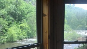 A room with a large window overlooking a river and dense greenery.