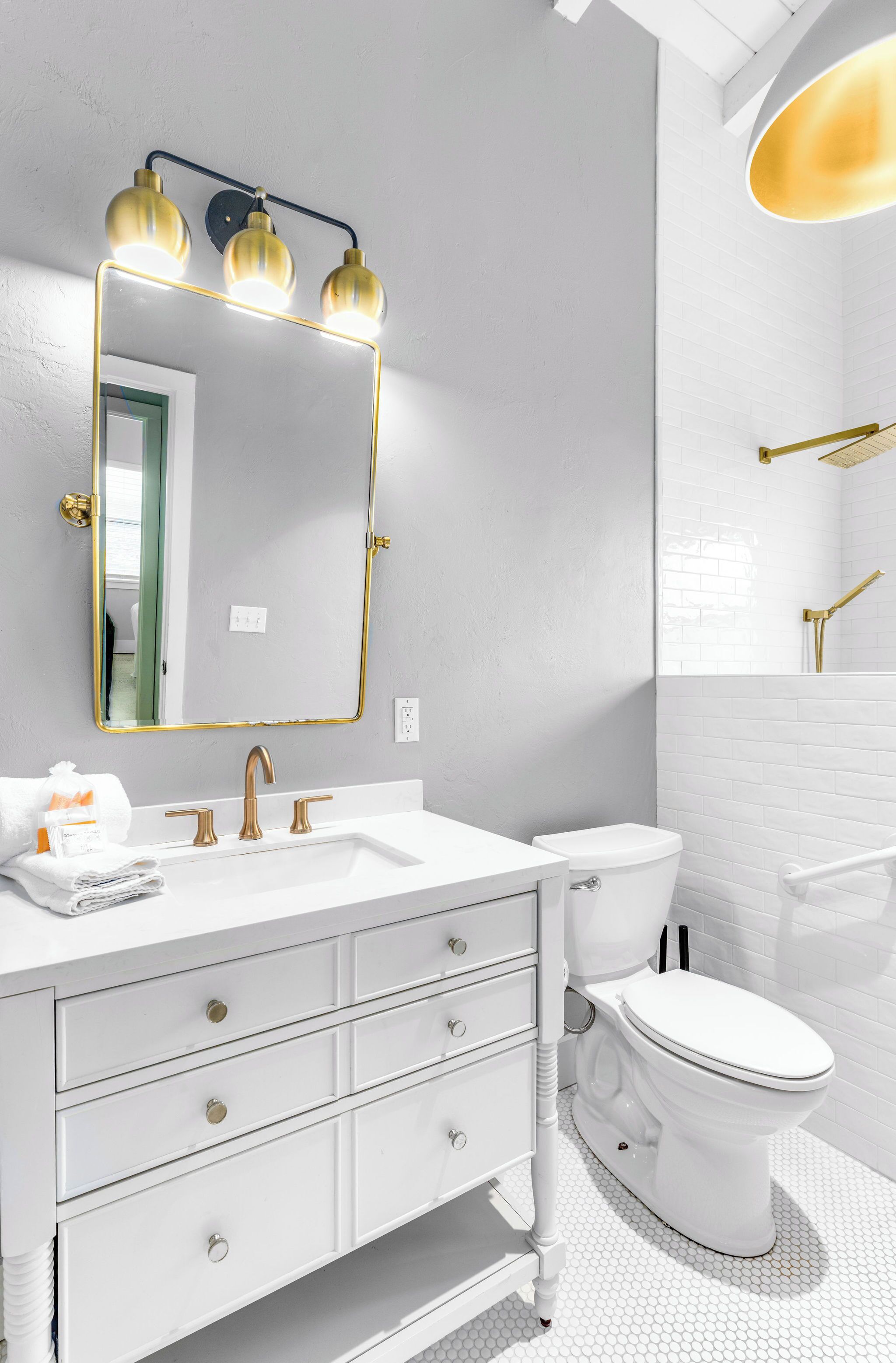 A bathroom with a white vanity, a gold-framed mirror, and a white toilet.