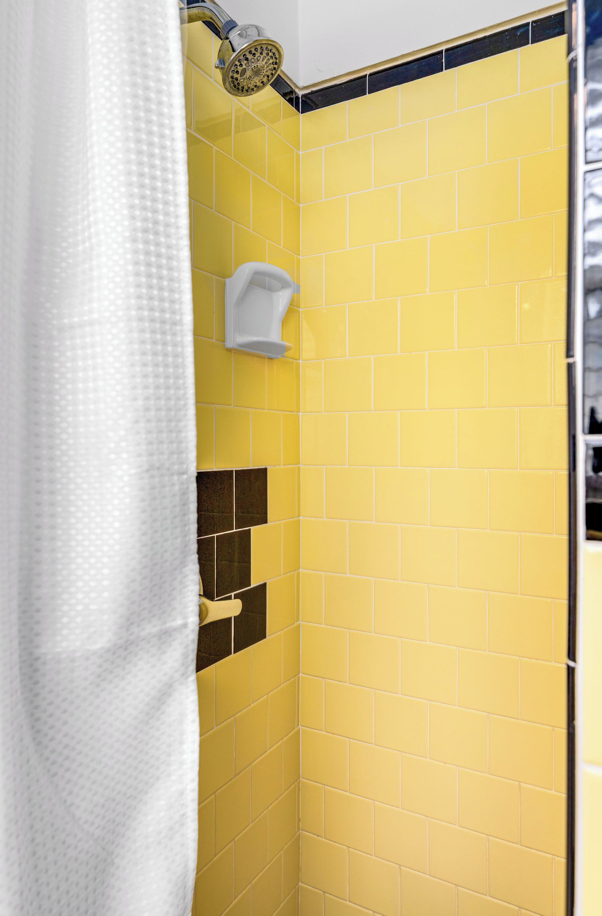 A bathroom with yellow tiles, a shower curtain, and a white towel rack.