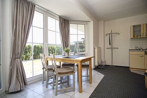 Una cocina moderna con comedor, ventanas amplias con cortinas y vistas a zonas verdes.