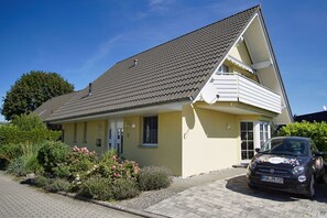 Ein zweistöckiges Haus mit geneigtem Dach, einer Satellitenschüssel und einem geparkten Auto auf der Auffahrt.