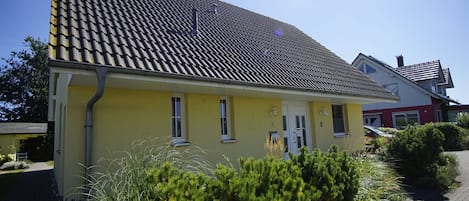 Ein gelbes Gebäude mit einem Ziegeldach, einer Tür und Fenstern.