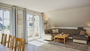 Ein geräumiges Wohnzimmer mit einer grossen Eckcouch, einem Holztisch und einem Essbereich mit Stühlen.