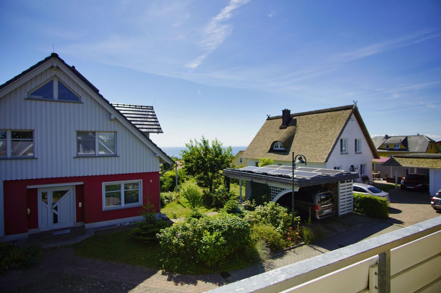A residential area with houses, including one with a red and white facade and another with a thatched roof.