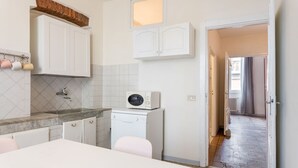 A kitchen with white cabinets, a microwave, and a washing machine. There is a window above the cabinets and a door leading to another room. - Appartamento Galgani -Affitti Brevi Italia (Lucca)