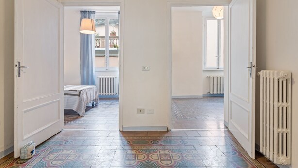 A hallway with patterned floor tiles, white doors, and a radiator on the right. - Appartamento Galgani -Affitti Brevi Italia (Lucca)