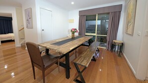 A dining area with a wooden table and benches, a vase with flowers, and a view through a window with curtains. - Family Holiday Entire House 8BRM Vermont (Vermont)