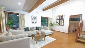 A modern living room with a sectional sofa, a glass coffee table, and a large window with curtains. - Family Holiday Entire House 8BRM Vermont (Vermont)