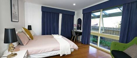 Un dormitorio con cama, mesita de noche, lámpara y sofá verde.