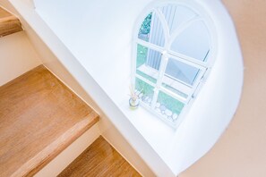 Eine Treppe mit Holzbodenstufen führt zu einer Empore mit einer weißen Wand und einem Fenster.