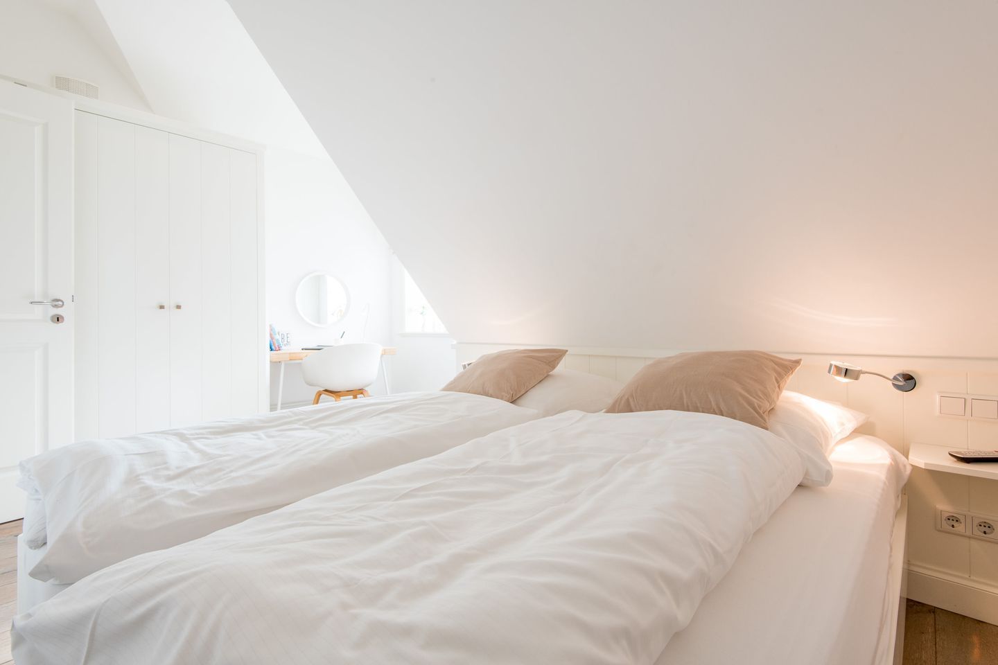 A bedroom with two beds, a desk, and a chair.