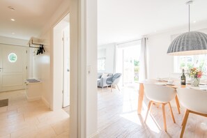 A modern kitchen with white cabinetry and a dining area with a white table and chairs.