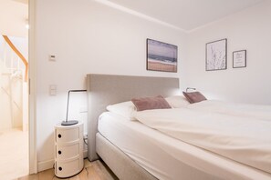 Un dormitorio con cama, lámpara de noche y mesita de noche.
