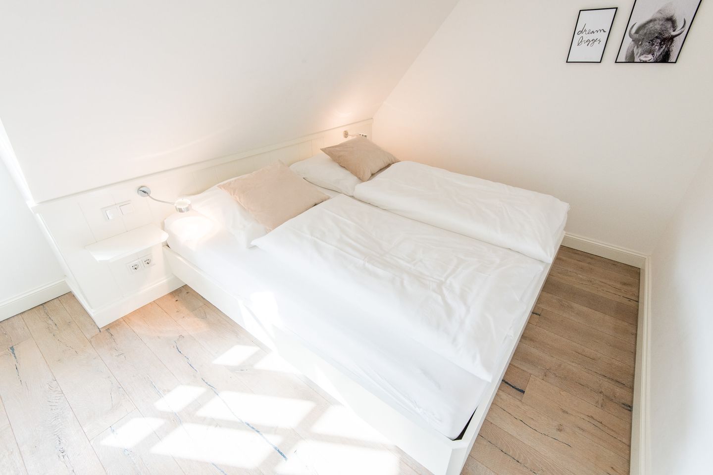 Un dormitorio con cama, mesitas de noche y una lámpara fijada a la pared.