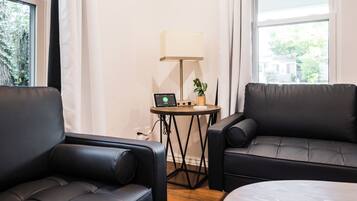 Una habitación con dos sofás de cuero negro, una mesita redonda con lámpara y un ordenador portátil.