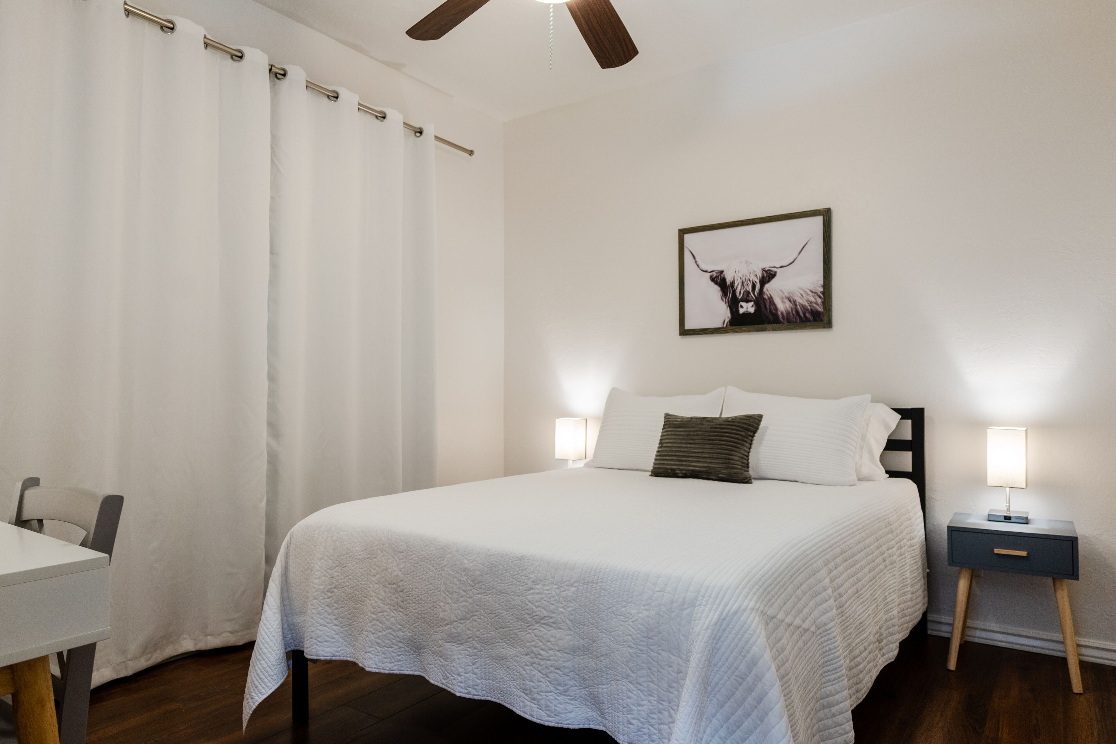 A neatly arranged bedroom with a bed, bedside tables, a chair, and a ceiling fan.