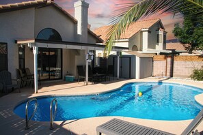 A swimming pool with a covered patio area, lounge chairs, and a brick wall. - Mediterranean House with Large Pool & Patio 10 min to strip & 5 min to Airport (Las Vegas)