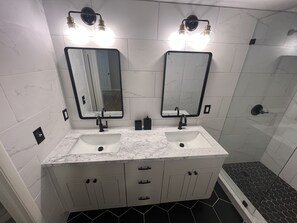 Une salle de bain avec deux lavabos, un miroir et une douche.