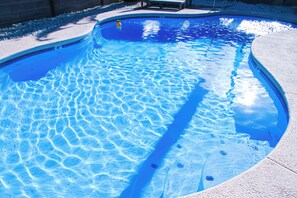Une piscine aux eaux cristallines, dotée d’un bord incurvé et d’une surface texturée.