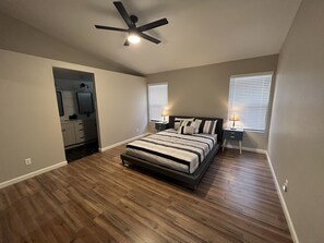A bedroom with a bed, a ceiling fan, and two bedside tables with lamps.