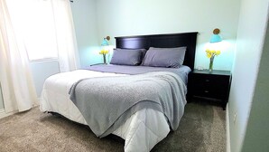 A bedroom with a bed, a ceiling fan, a nightstand with a lamp, and a window with curtains. - Beautiful Casita, Pet Friendly, Full RV Hookups & Boat Parking (Page)