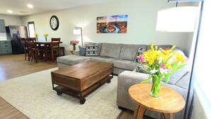 A spacious living room with a wooden coffee table, a gray sofa, and a dining area with a wooden table and chairs. - Beautiful Casita, Pet Friendly, Full RV Hookups & Boat Parking (Page)
