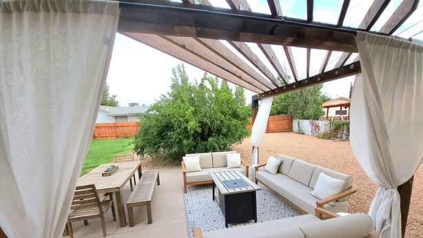 A covered patio area with a wooden table and chairs, a sofa, and a small rug. - Beautiful Casita, Pet Friendly, Full RV Hookups & Boat Parking (Page)