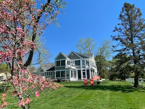 A two-story house with a large front porch, a covered patio, and a well-maintained lawn.