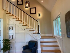 A staircase with white railings and wooden steps, a blue chair, and framed pictures on the wall.