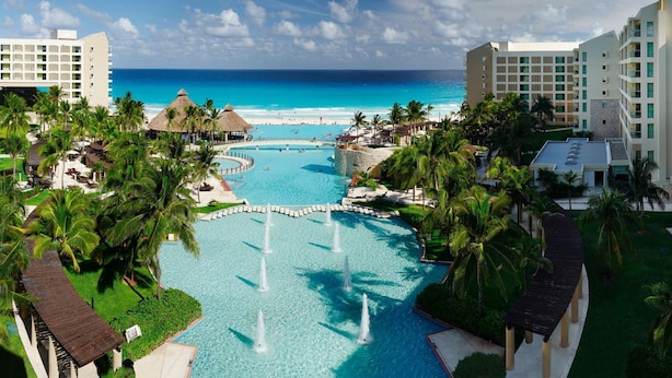 A resort with a central swimming pool, palm trees, and beachfront views. - 2 Bedroom - Westin Lagunamar Ocean Resort - Full Resort Access (Cancún)