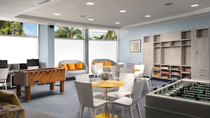 A modern indoor space with a foosball table, a sofa, a dining table with chairs, and a storage area with shelves. - 2 Bedroom - Westin Lagunamar Ocean Resort - Full Resort Access (Cancún)
