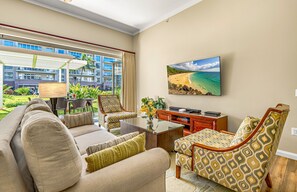 A living room with a sofa, armchairs, a coffee table, and a flat-screen TV mounted on the wall.