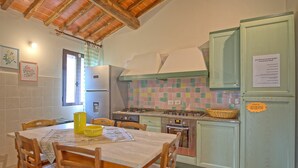 Une cuisine avec des meubles en bois, un pare-feu en carreaux et une table à manger avec des chaises.