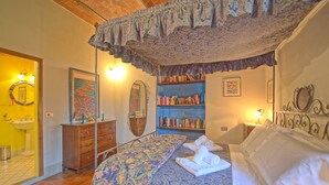 Une chambre à coucher avec un lit, une bibliothèque, un miroir et une salle de bain visible au fond.