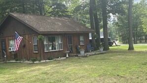 Une cabane en bois avec un porche, un drapeau américain et des plantes en pot.