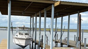 A boat docked at a pier with a covered walkway and fishing rods. - Sargent Beach House Getaway - fish from the dock and walk to the beach! (Sargent)