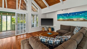 A spacious living room with a large sectional sofa, a flat-screen TV, and a wooden coffee table.