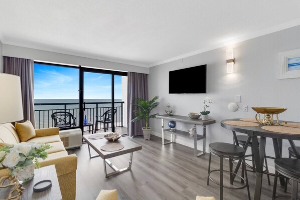 A modern hotel room with a balcony, a dining area, and a living space. - Impressive Oceanfront Suite on the 11th Floor (Myrtle Beach)