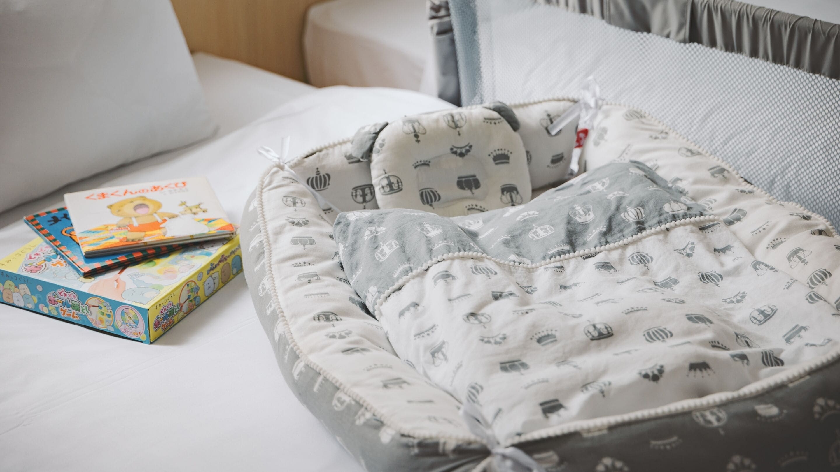 Un letto rifatto con un cuscino a motivi grigi e bianchi e un libro accanto.