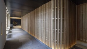 Un pasillo con pared de listones de madera, un mostrador de recepción y una planta en maceta.