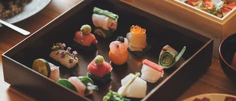 A wooden table with a variety of food items, including sushi and other appetizers.