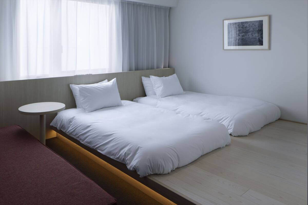 Una habitación de hotel moderna con una cama grande, una mesita redonda y un sofá rojo.