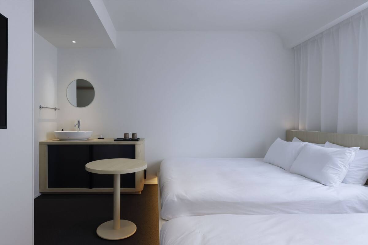 Una habitación de hotel moderna con una cama, una mesa redonda, un lavamanos y un espejo.