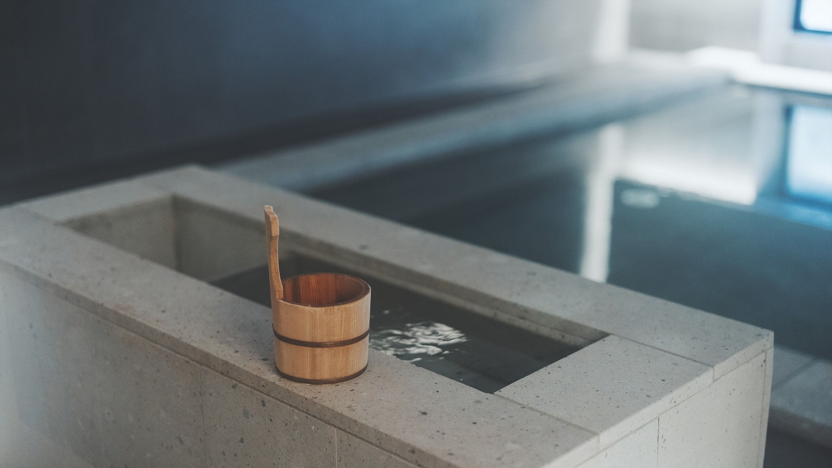 A small wooden cup with a handle on a concrete ledge.