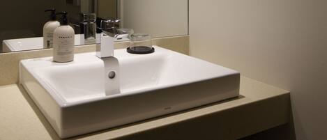 A white bathroom sink with a mirror above it, a soap dispenser, and a faucet.