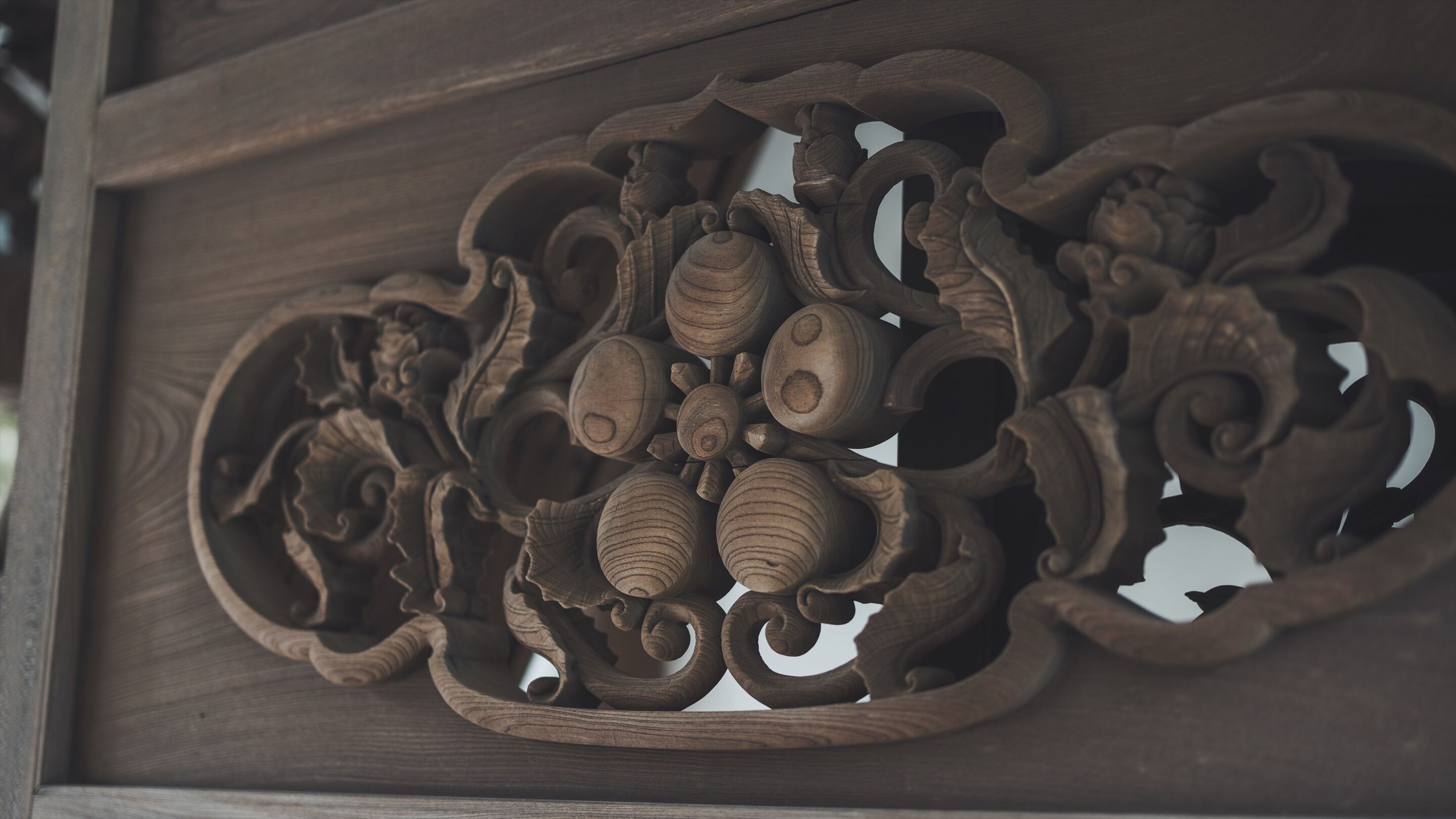 Un panel de madera tallado con detalle, adornado con diseños intrincados y múltiples motivos circulares.