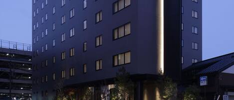 Un hotel de varios pisos con fachada oscura y ventanas iluminadas.